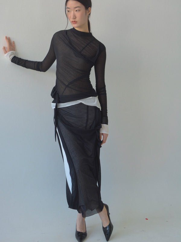 Person wearing a black and white outfit against a plain background